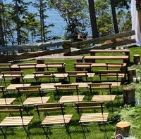 A wedding ceremony with wooden benches and chairs.