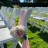 A row of white chairs with pink flowers on them.