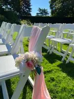 A row of white chairs with pink flowers on them.