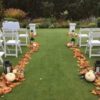 A wedding ceremony with pumpkins and lanterns on the grass.