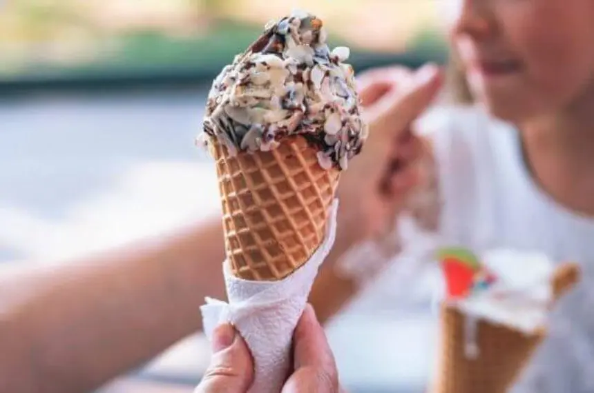 A person holding an ice cream cone in their hand.