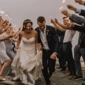 A bride and groom are walking through the crowd.