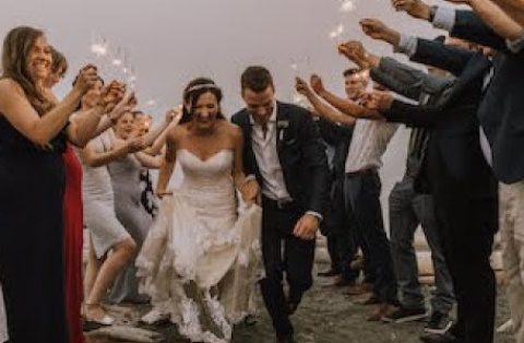 A bride and groom are walking through the crowd.