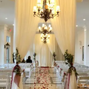 A wedding ceremony with white drapes and red roses.