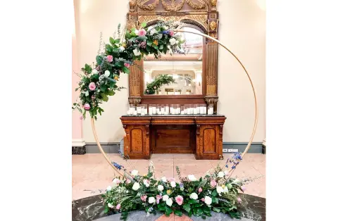 A large round floral arrangement in front of a mirror.