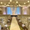 A wedding ceremony with white chairs and lights.