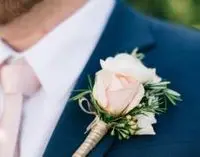 A man in blue suit and white rose boutonniere.