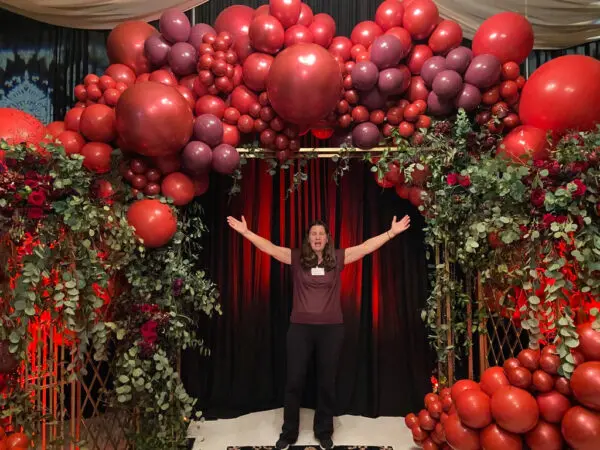 A woman standing in front of an arch made out of balloons.