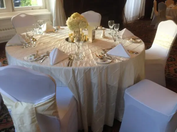 A table set with white chairs and gold linens.