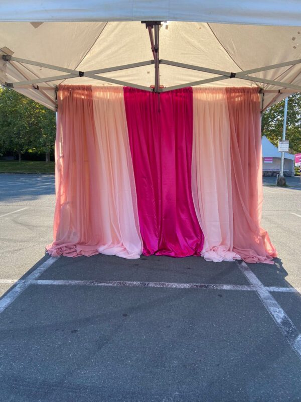 A pink and white tent with curtains on the side.