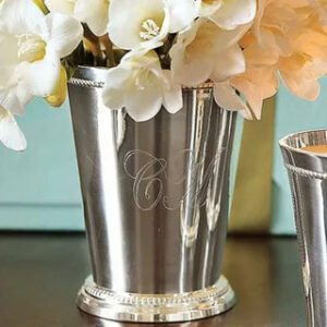 A silver vase with flowers in it on top of a table.