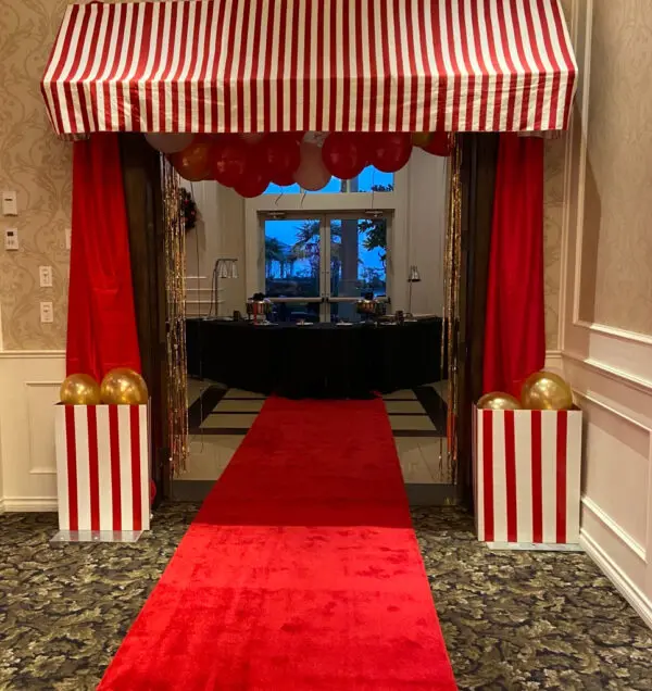 A red carpet with a striped tent and gold balls.