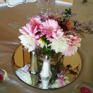 A vase of flowers on top of a mirror.