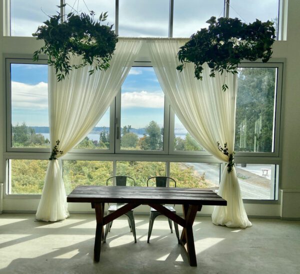 A table in front of two large windows with curtains.