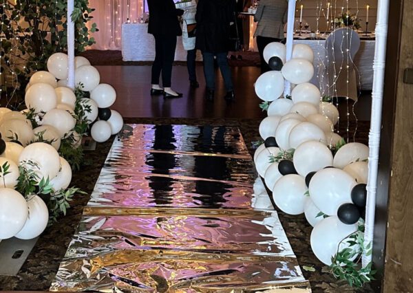 A walkway with balloons and silver foil on it.