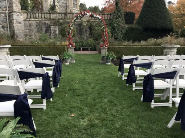 A wedding ceremony with white chairs and blue covers.