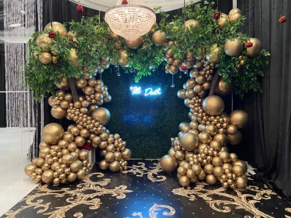 A room with gold balloons and greenery