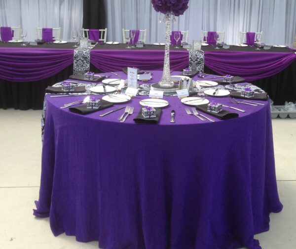 A table set up with purple linens and black napkins.