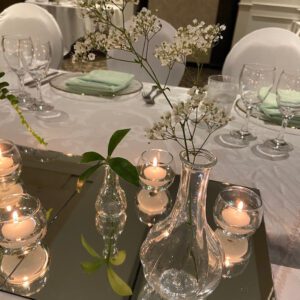 A table set with candles and vases on top of it.