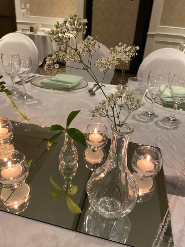 A table set with candles and vases on top of it.