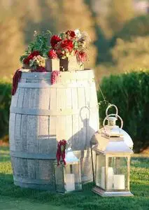 A barrel with flowers and candles on top of it.