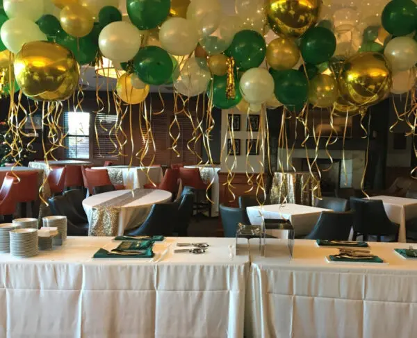 A room with tables and chairs, balloons hanging from the ceiling.