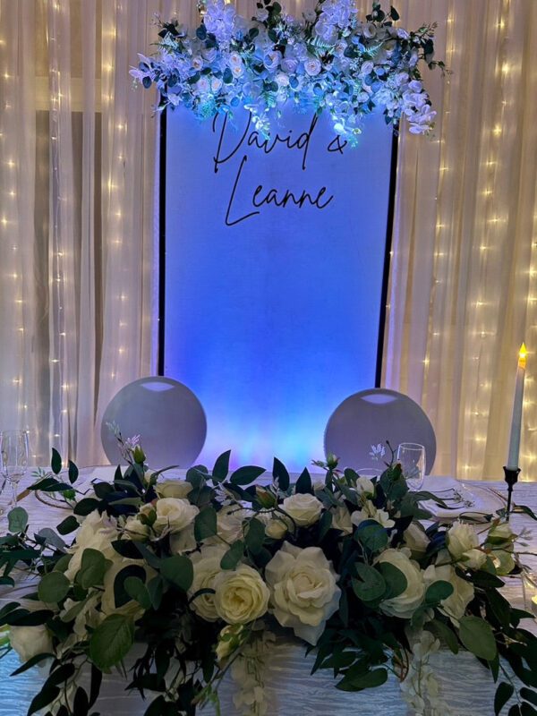 A table with flowers and lights in front of the name