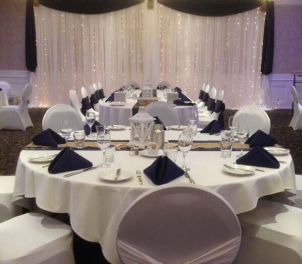 A table set with white linen and black napkins.