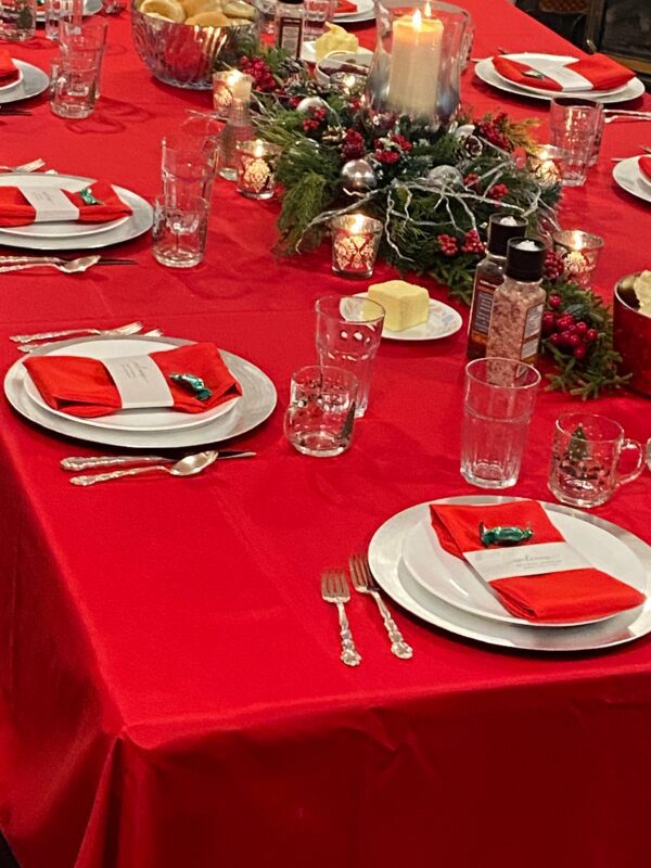 A table set with red and white plates, silverware, candles.