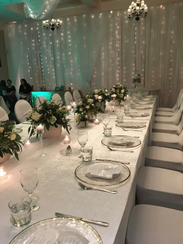 A long table with white plates and flowers on it