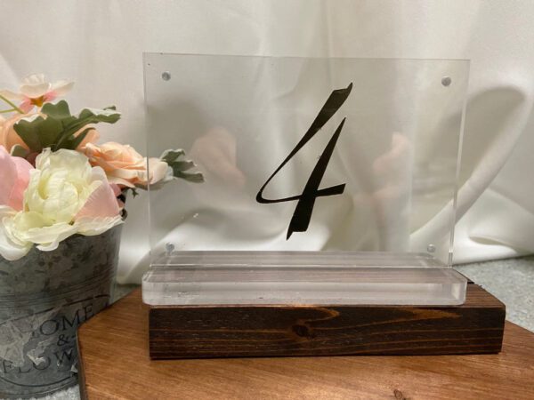 A table number with a wooden base and clear plastic holder.