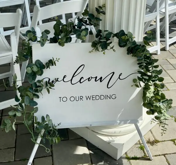 A white sign with the words " welcome to our wedding ".