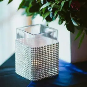 A candle holder with silver rhinestones on top of a table.