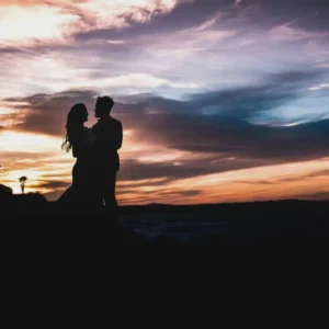 A couple is standing in the sunset