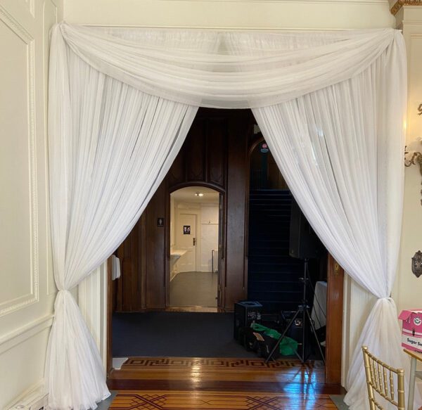 A doorway with white curtains and wood floors.