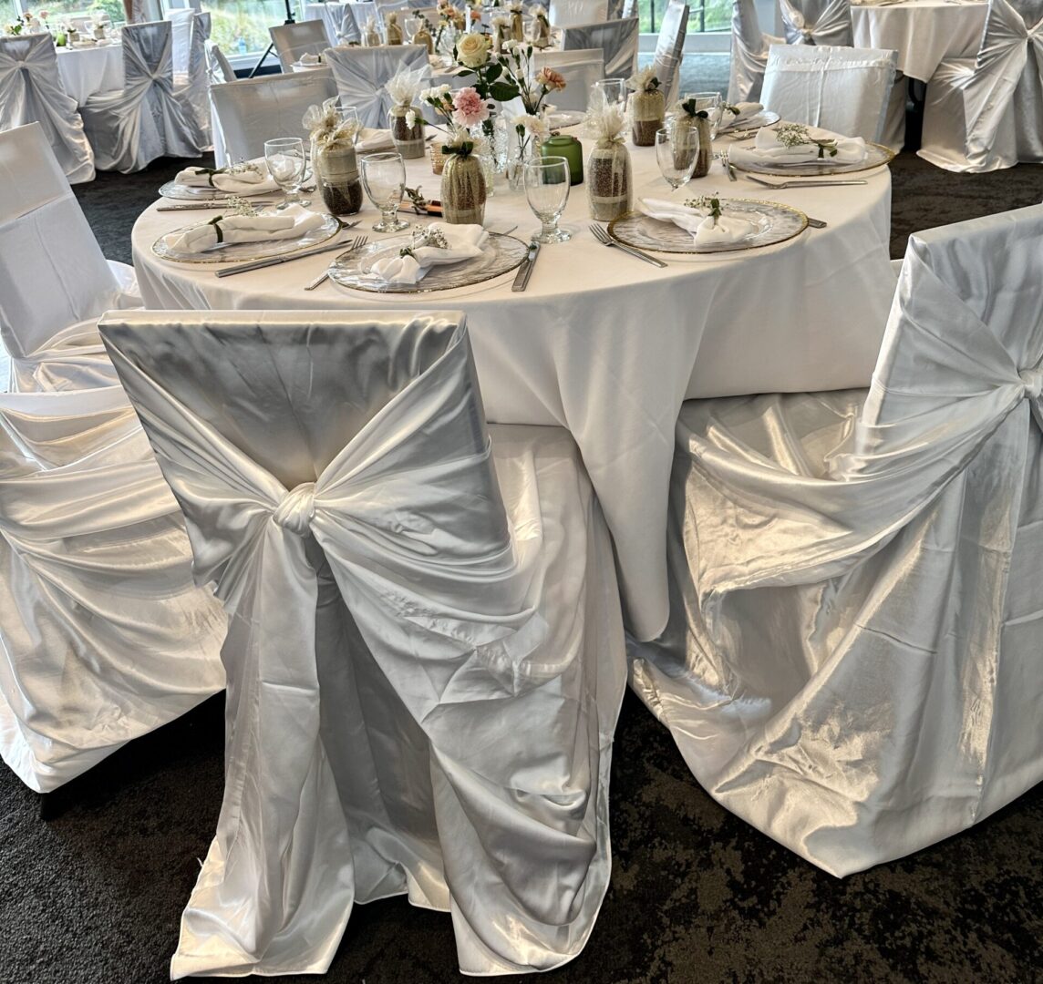 A table set with white linens and chairs.