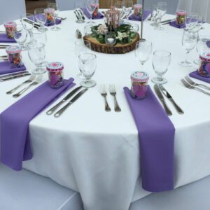 A table set with purple napkins and silverware.