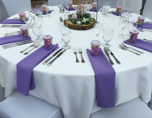 A table set with purple napkins and silverware.