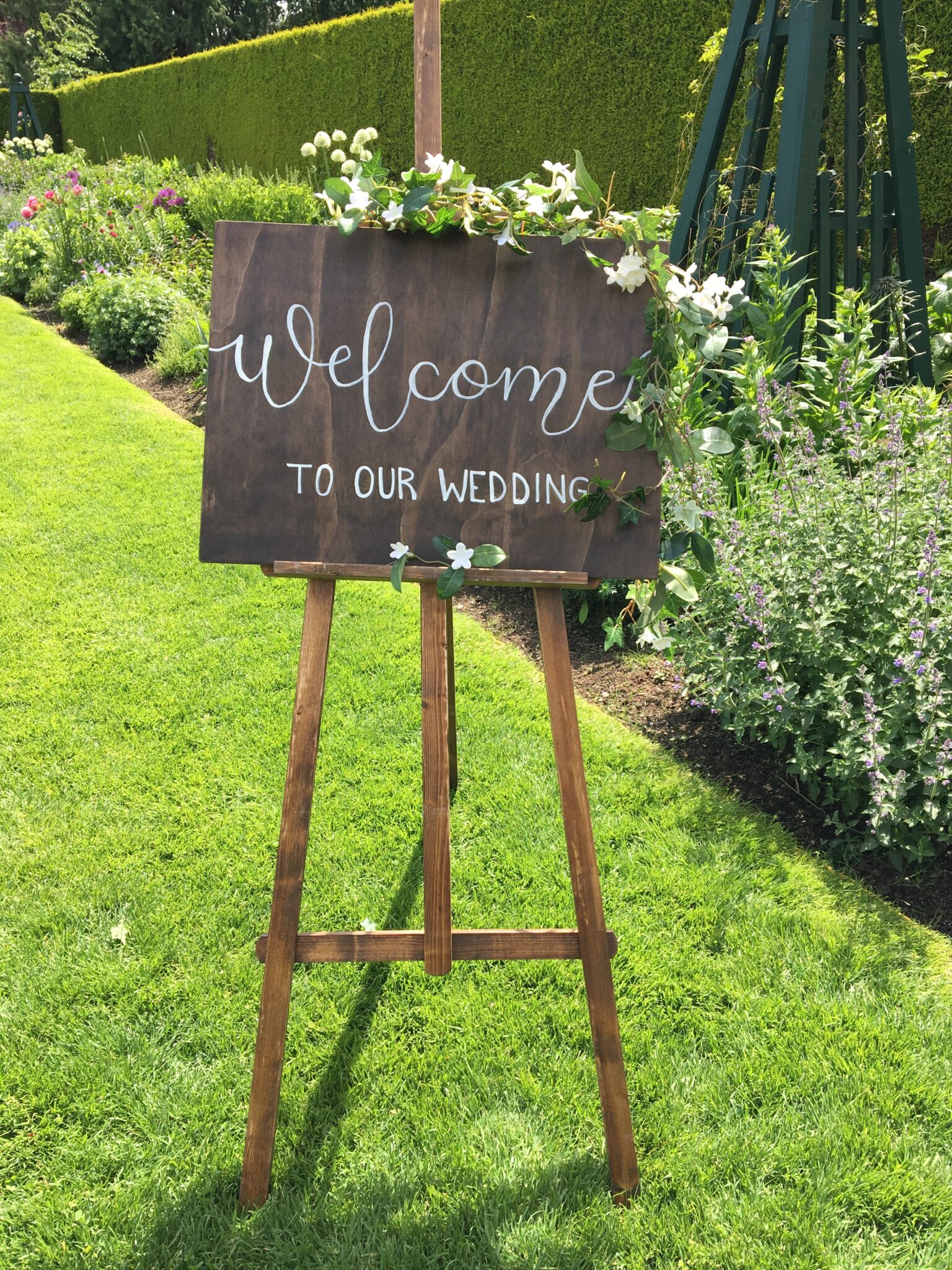 A wooden sign that says welcome to our wedding.