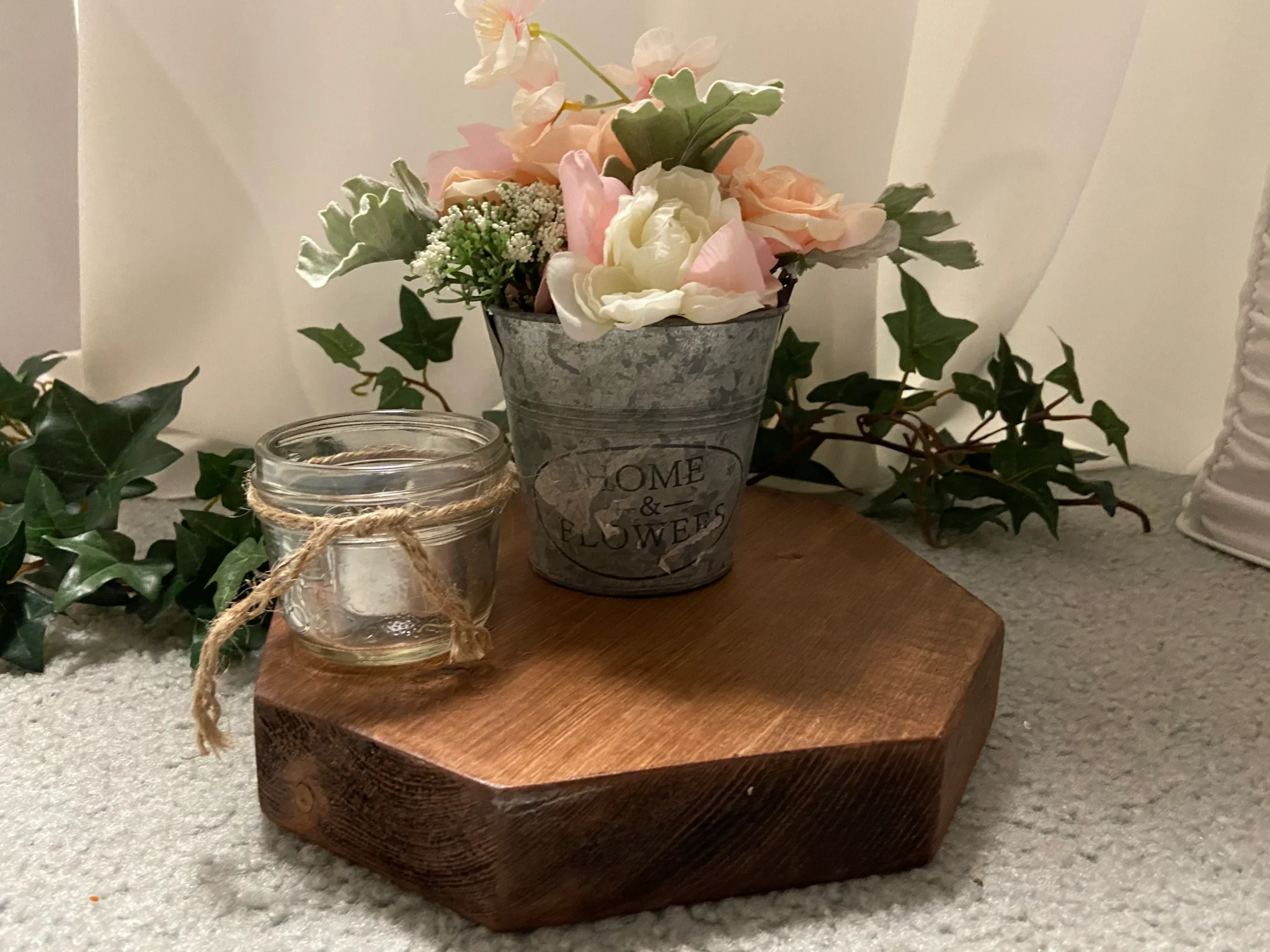 A wooden board with flowers in it and a candle.