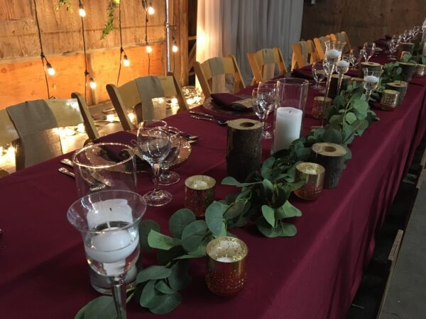 A long table with candles and greenery on it