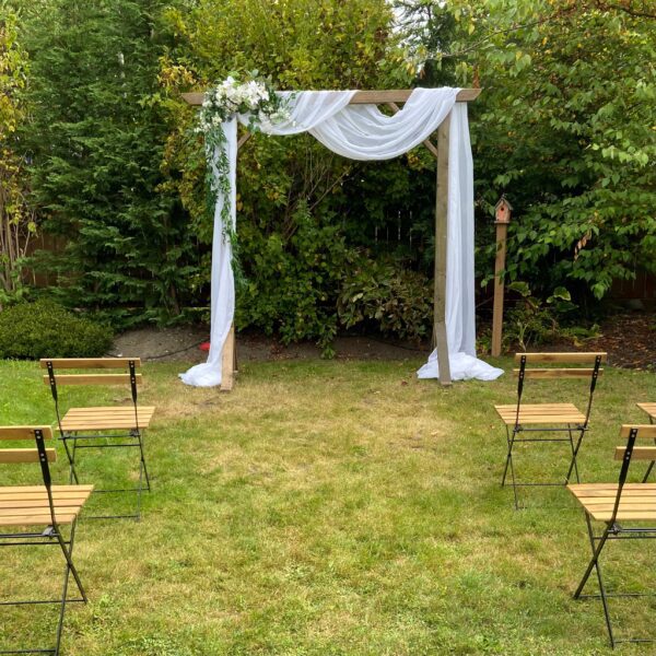 A wedding arch and chairs in the grass.