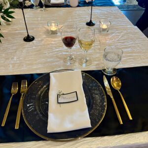 A table set with plates, silverware and wine glasses.