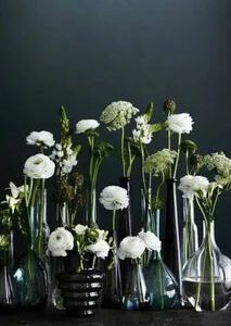 A group of white flowers in vases on top of each other.