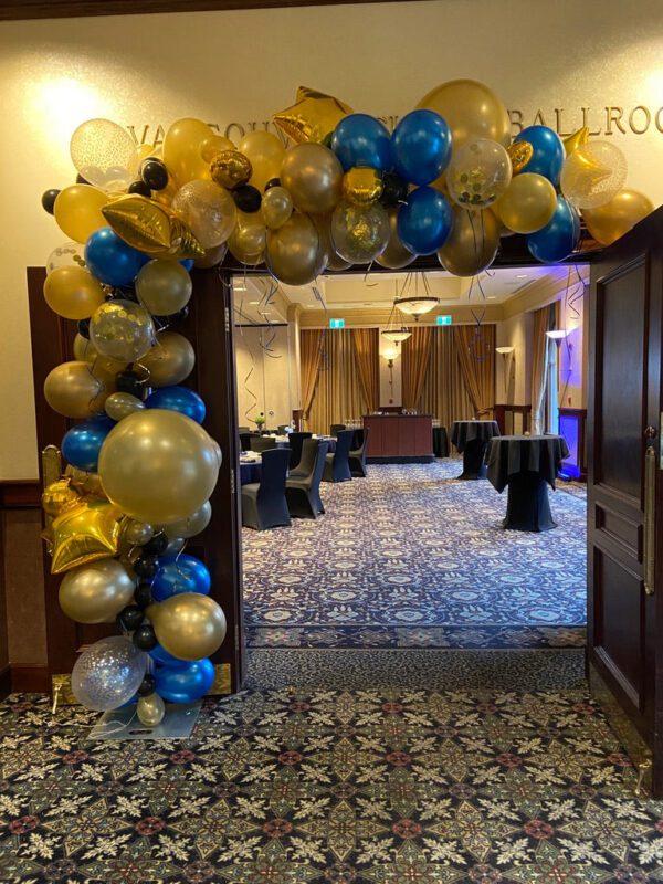 A room with balloons and blue, white and gold decorations.