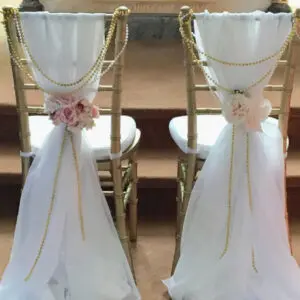 Two chairs with white and gold decorations on them