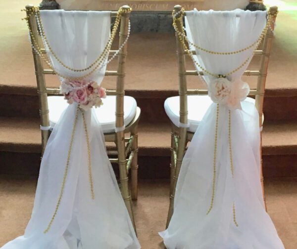 Two chairs with white and gold decorations on them