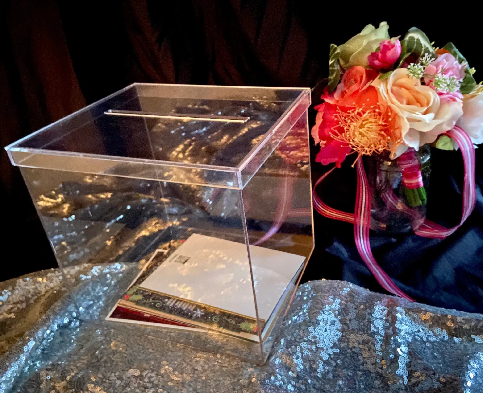 A clear box with flowers in it on top of a table.