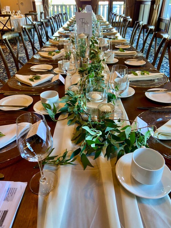 A long table with plates, cups and glasses on it.