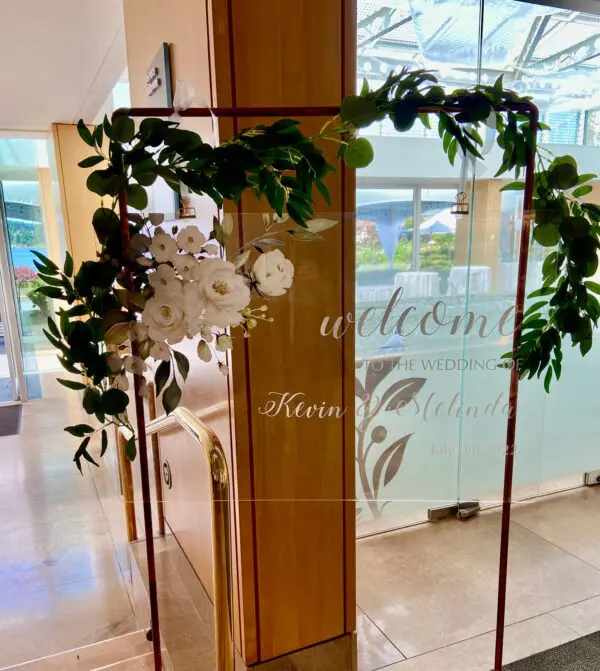 A glass door with flowers and greenery on it.